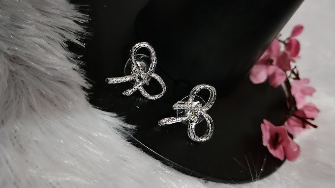 Yoniq.woman silver-tone bow stud earrings with a textured metallic finish and delicate knotted ribbon design.