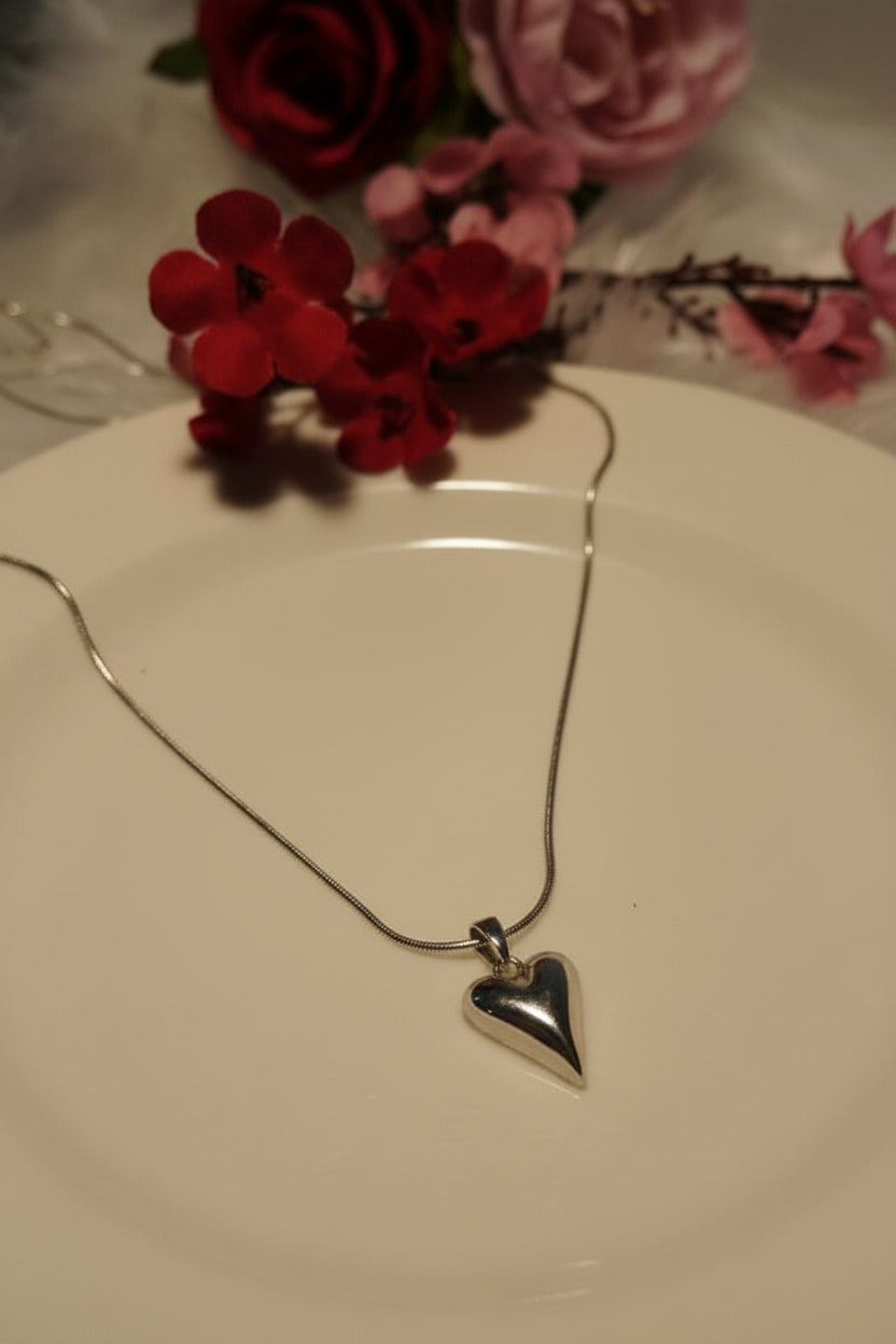 Yoniq.woman silver-tone heart pendant necklace with a polished finish on a delicate chain against a white plate