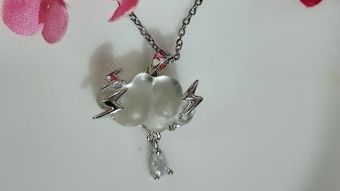 Yoniq.woman cloud and lightning bolt pendant necklace with a teardrop crystal charm on a silver chain near pink flowers