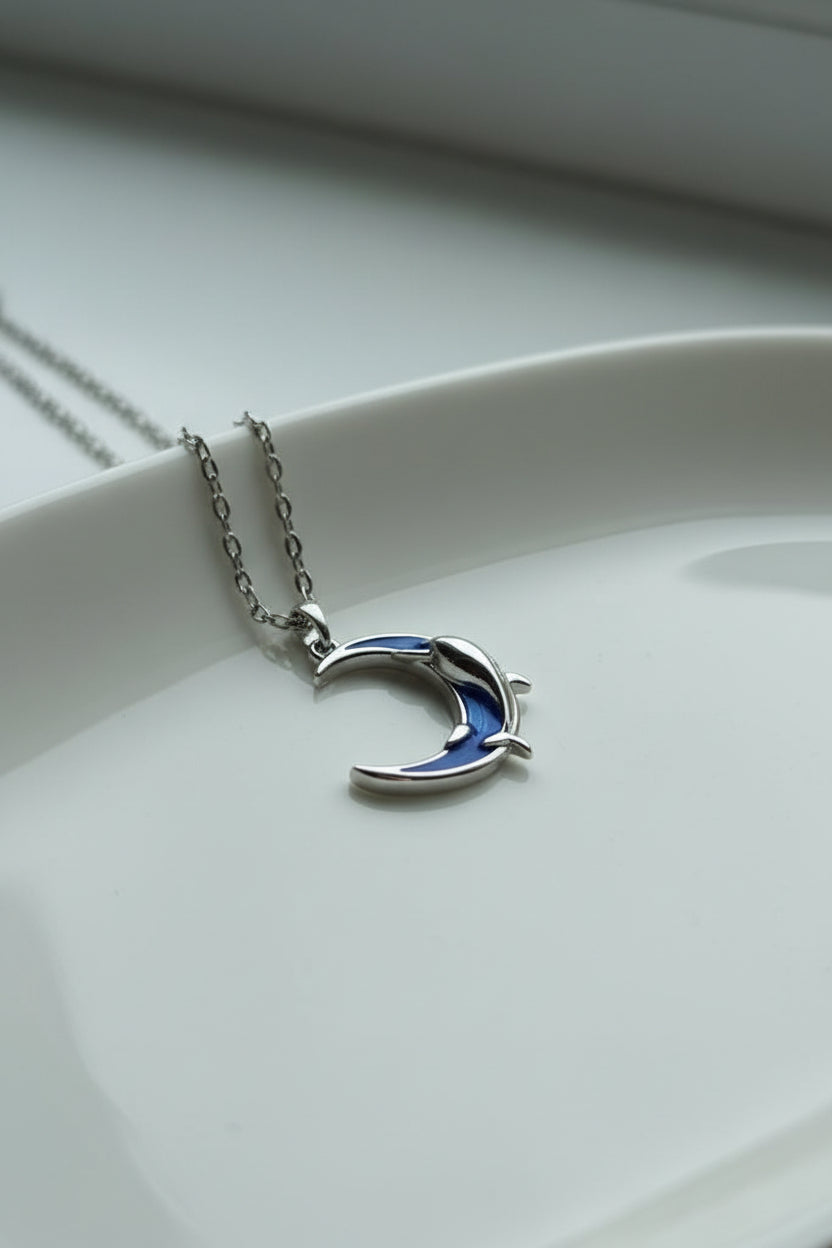 Yoniq.woman silver-tone crescent moon and dolphin pendant necklace with deep blue enamel inlay on a delicate chain.