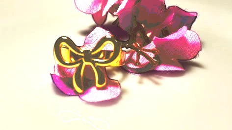 Yoniq.woman gold-tone adjustable bow ring with a polished finish resting on a purple flower petal