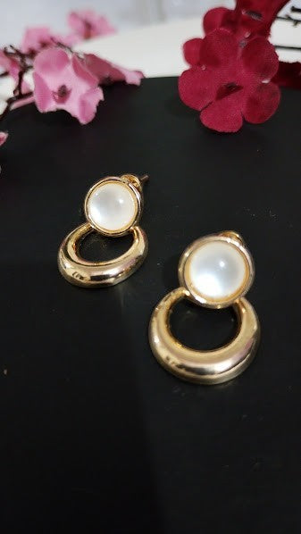 Yoniq.woman gold-tone circular drop earrings featuring a smooth white cabochon stud on a polished metallic base.