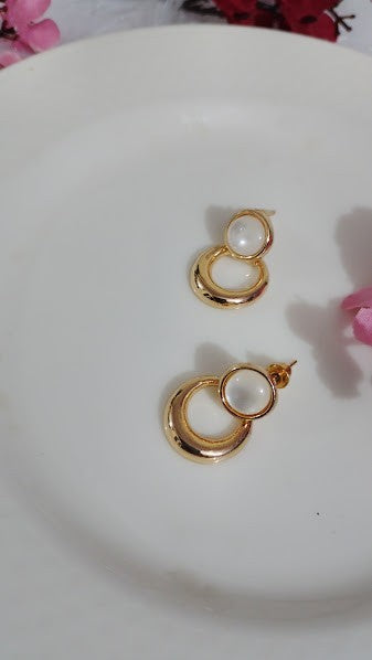 Yoniq.woman gold-tone circular drop earrings with smooth white cabochon studs on a white plate