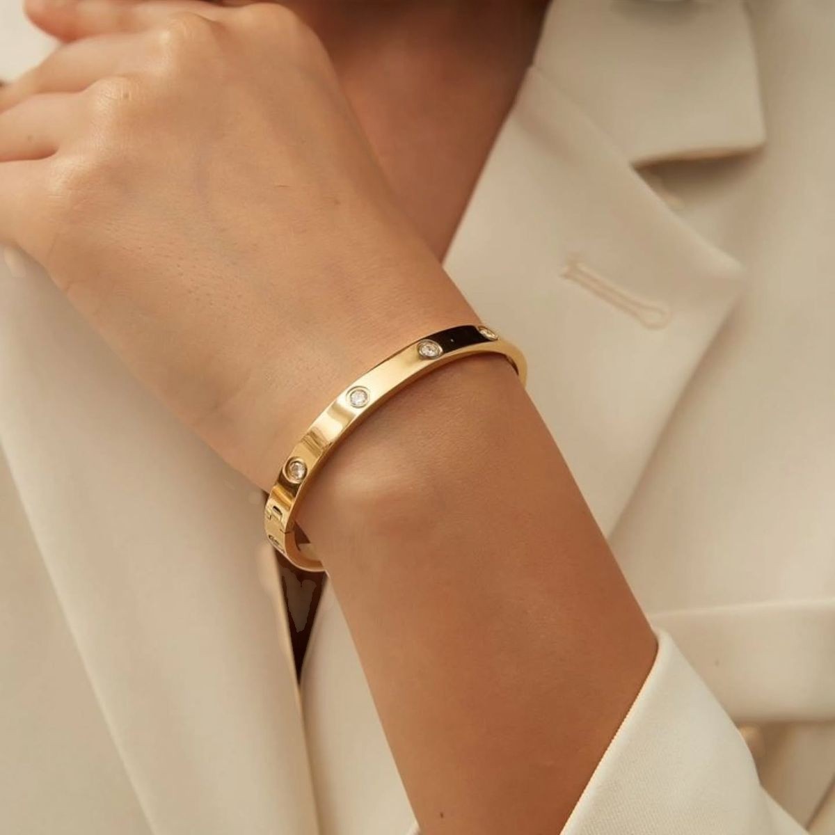 Yoniq.woman gold-tone minimalist bangle bracelet with crystal inlays and screw-head motifs worn on a wrist