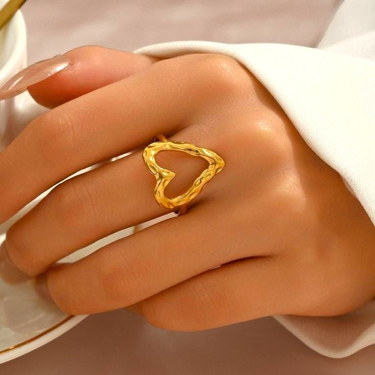Yoniq.woman gold-tone open heart ring with a hammered texture worn on a finger, showcasing a minimalist design.