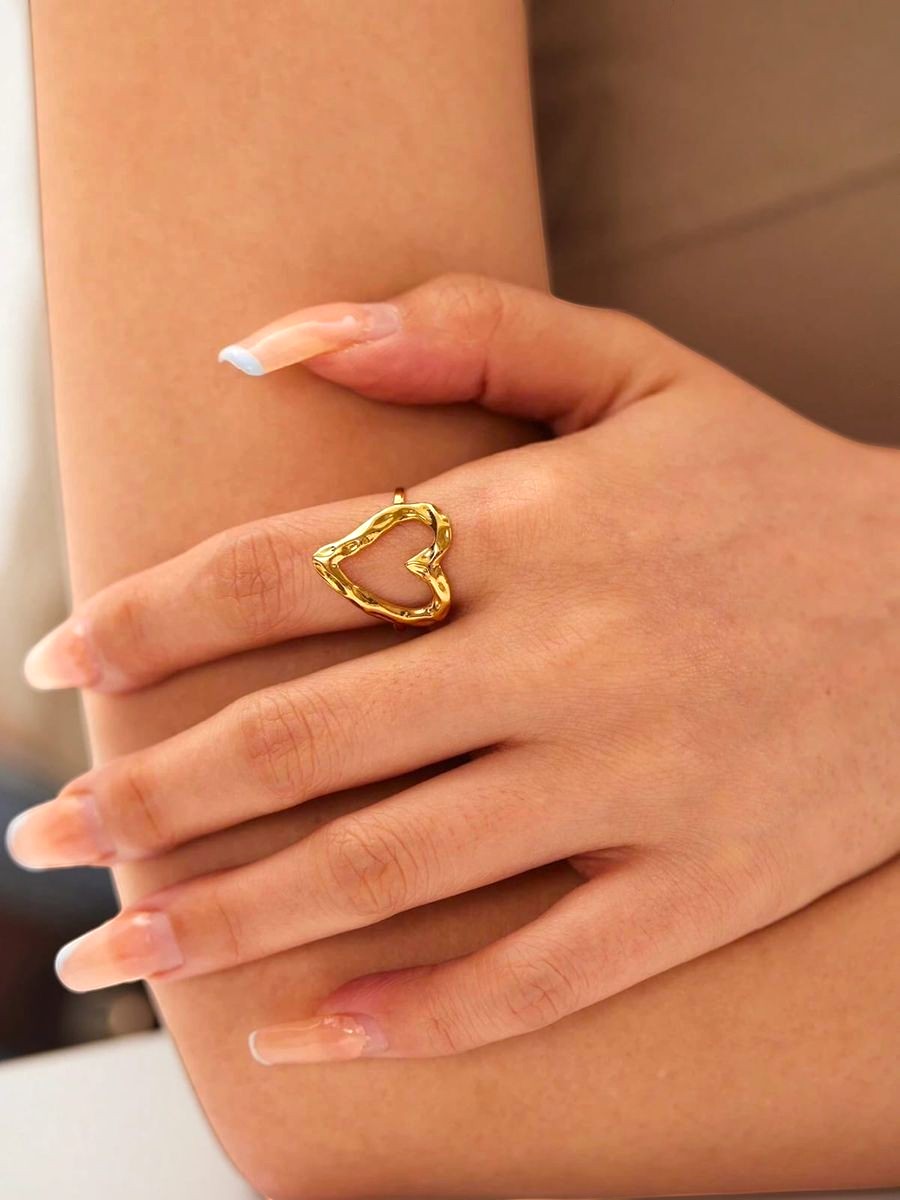Yoniq.woman gold-tone open heart ring with a hammered texture worn on a finger for a minimalist, elegant look.