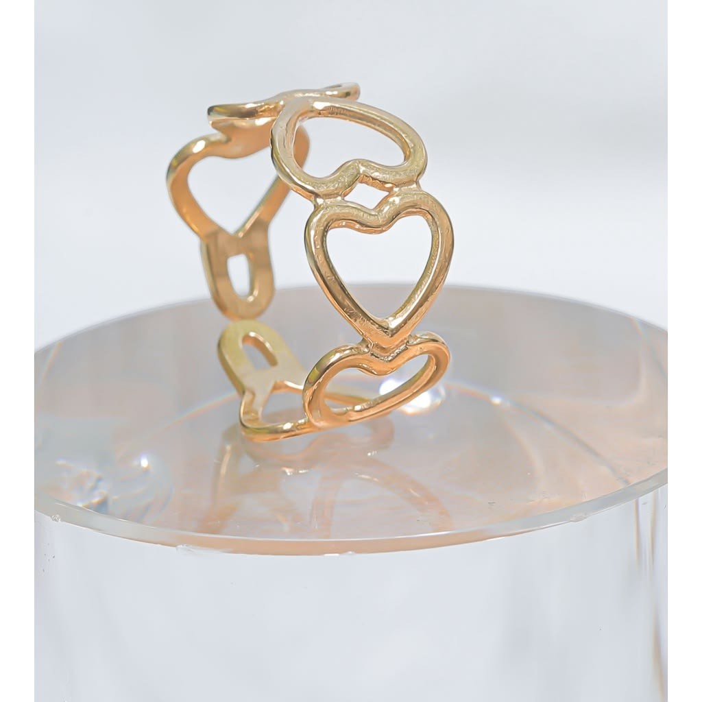 Yoniq.woman gold-tone adjustable statement ring featuring a continuous open heart motif on a clear display stand.