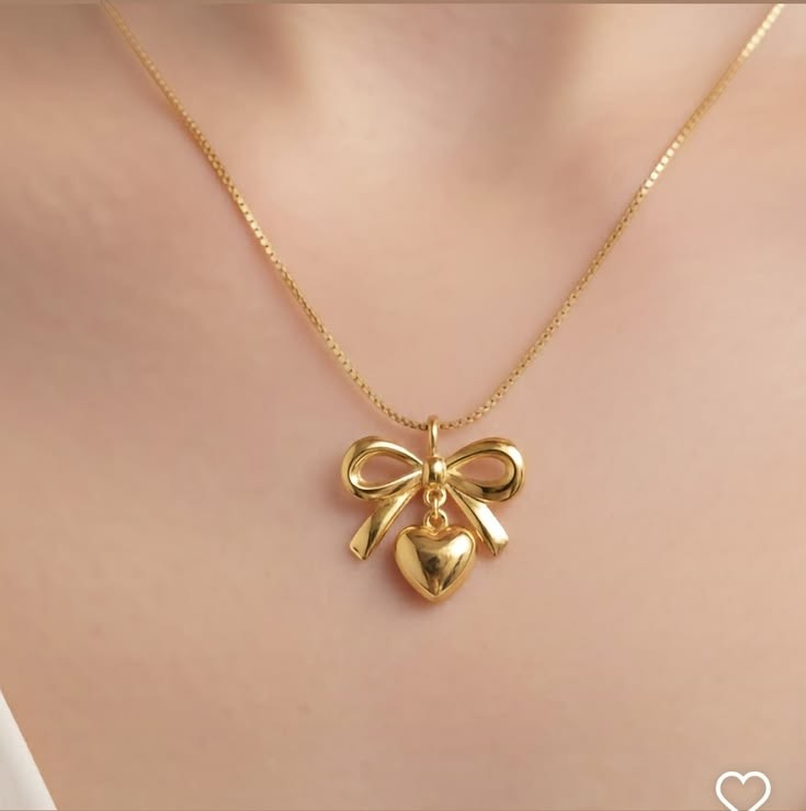 Yoniq.woman gold-tone necklace featuring a polished heart and bow pendant on a delicate chain worn on a neckline