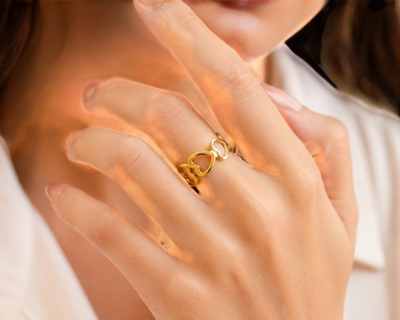 Yoniq.woman gold-tone adjustable statement ring featuring an interconnected open heart motif worn on a finger