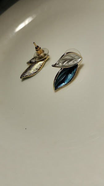 Yoniq.woman elegant leaf-shaped stud earrings with blue and white enamel and gold-toned metal edges.