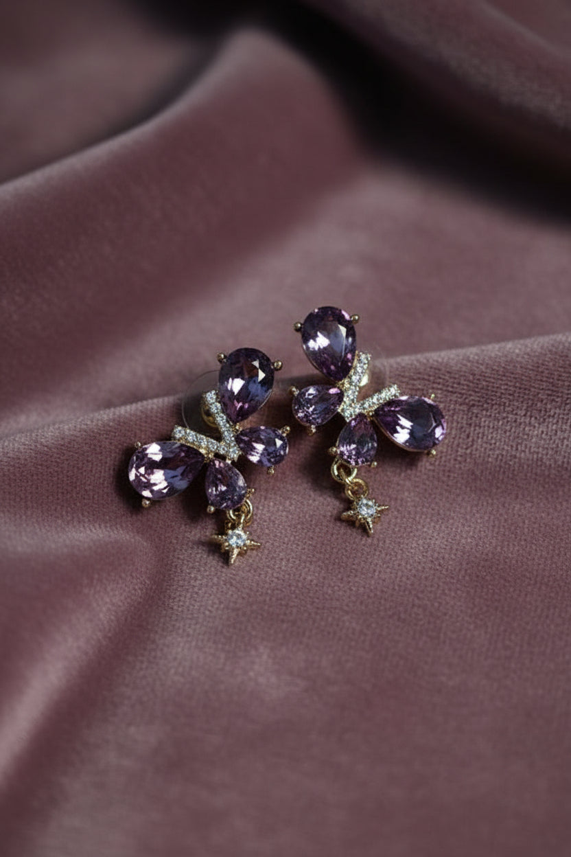 Yoniq.woman butterfly stud earrings with purple teardrop crystals, gold-tone setting, and dangling star charms.