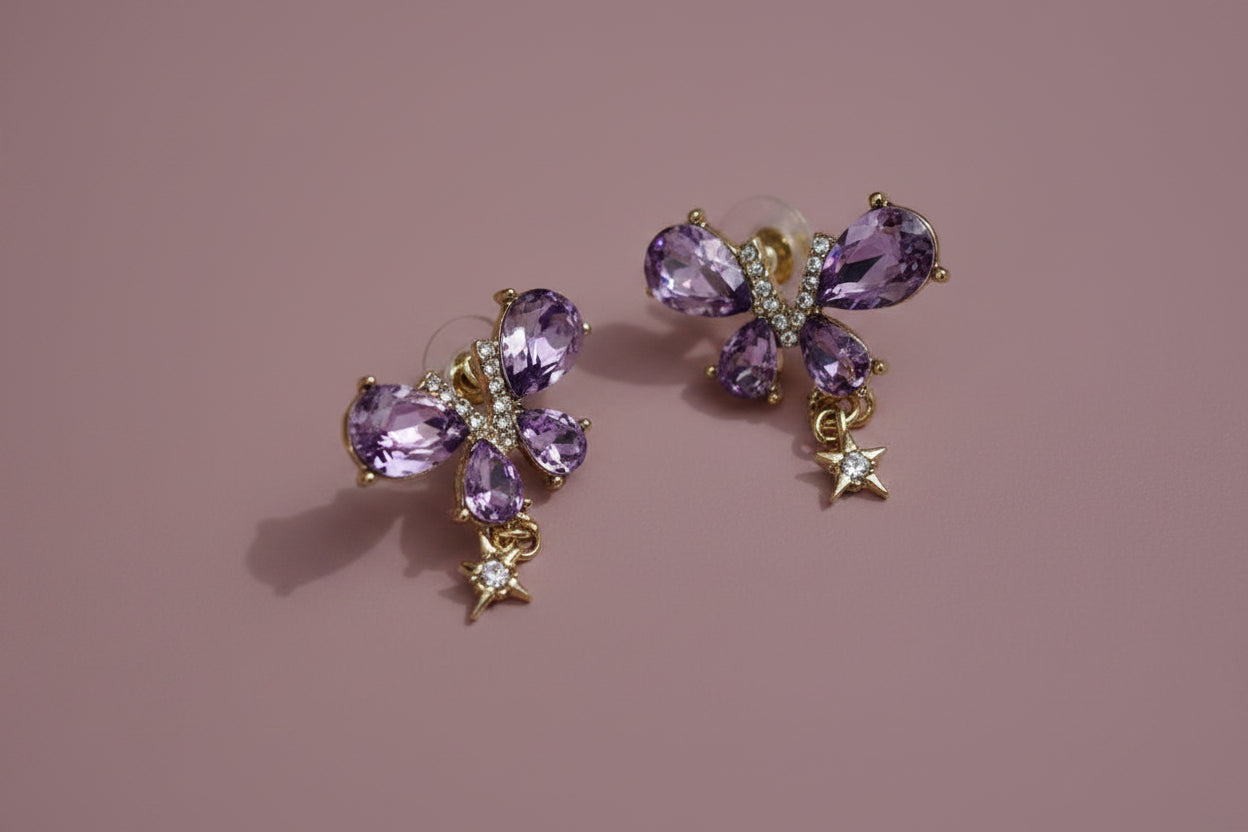 Yoniq.woman butterfly stud earrings with purple teardrop crystals, gold-tone setting, and dangling star charms.
