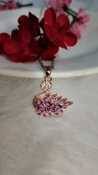 Yoniq.woman rose gold swan pendant necklace featuring marquise-cut purple crystals and pavé detailing