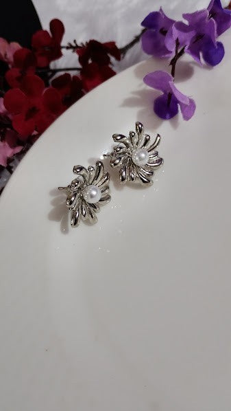 Yoniq.woman silver-tone floral stud earrings featuring an abstract petal design and a central faux pearl accent.