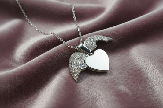 Yoniq.woman silver-tone heart locket necklace with cubic zirconia wings and a central stone on a delicate chain.