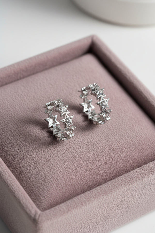Yoniq.woman silver-tone hoop earrings featuring a row of sparkling crystal-accented stars on a white plate with flowers